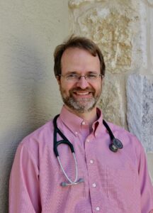 Picture of Dr. Thomas, Family Medicine Physican. Thomas is smiling. He's wearing a pink shirt and stethoscope.